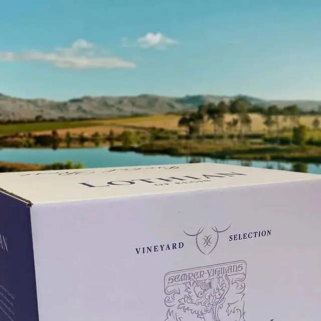 A Lothian Vineyards wine box in front of a dam and mountains in Elgin