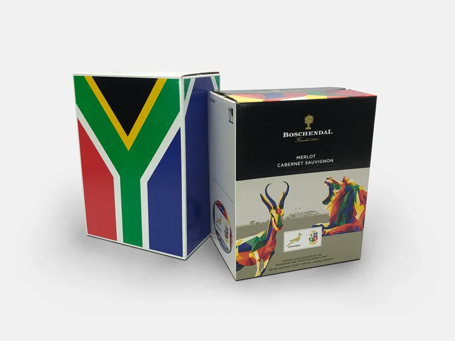 A wine box printed with the South African flag beside a Boschendal Merlot Cabernet Sauvignon box with a springbok and lion